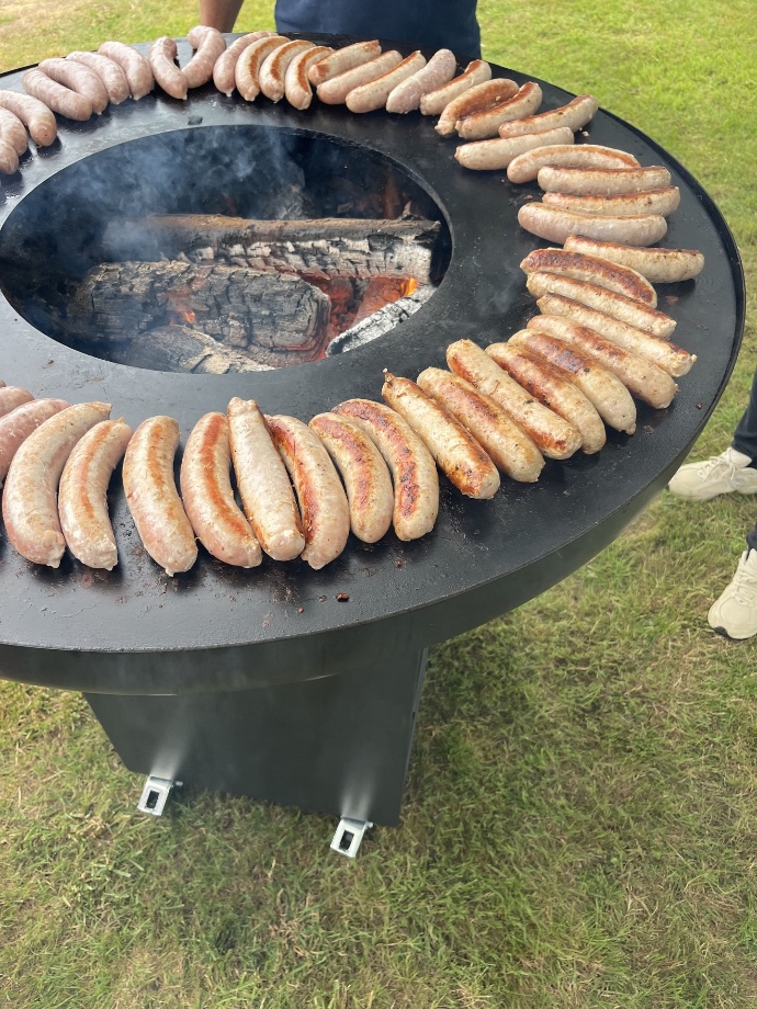 Cuisson de nombreuses saucisses sur un brasero lors d’un événement convivial